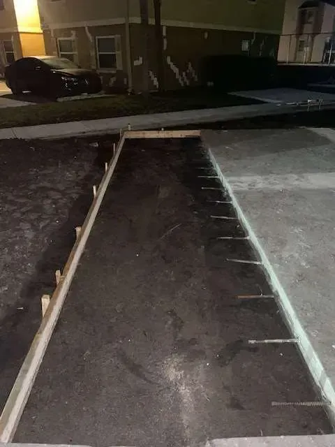 Concrete work in progress at night; wooden frame outlines a rectangular section for pouring.