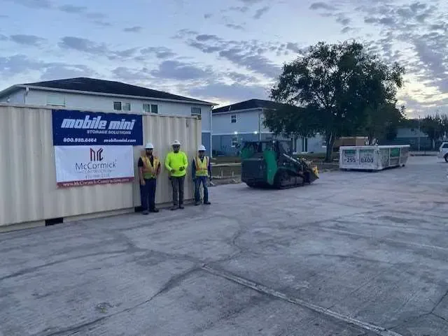 Three men stand beside a mobile storage container labeled 