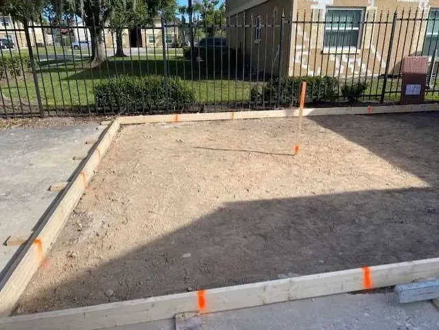 Wooden frame outlining a square area on a sandy surface. Orange markers are present.