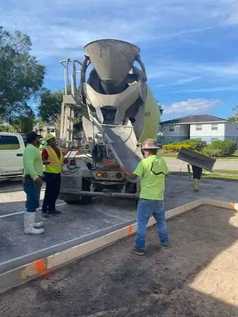 Construction workers pouring concrete from a truck into a prepared frame outdoors.