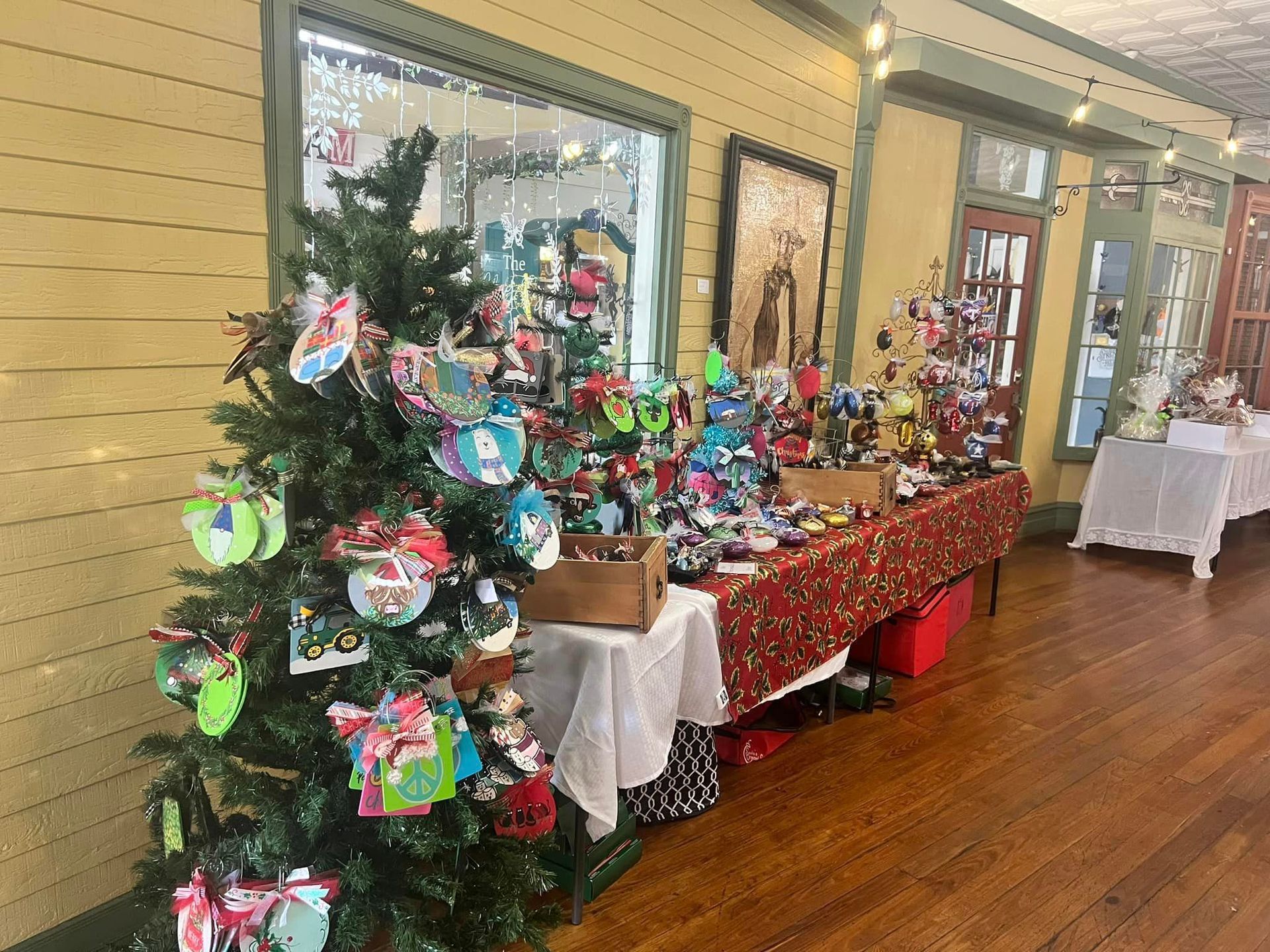 Christmas decorations displayed for sale in a shop; tree, table of ornaments, festive setting.