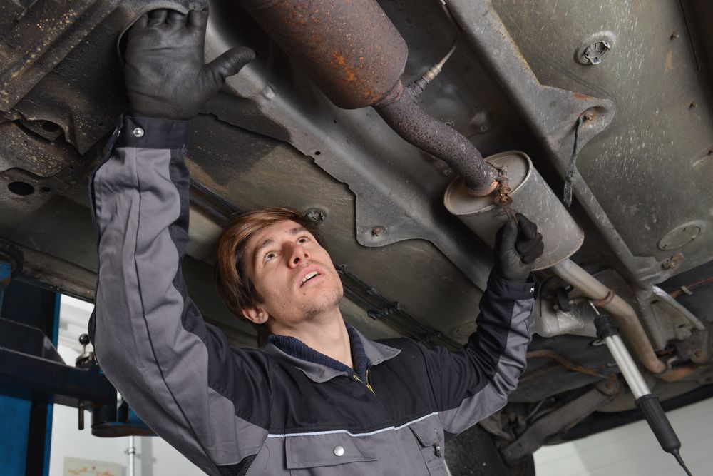 Mechanic Under a Car Examining the Exhaust — Morty's Mechanical In Garbutt, QLD