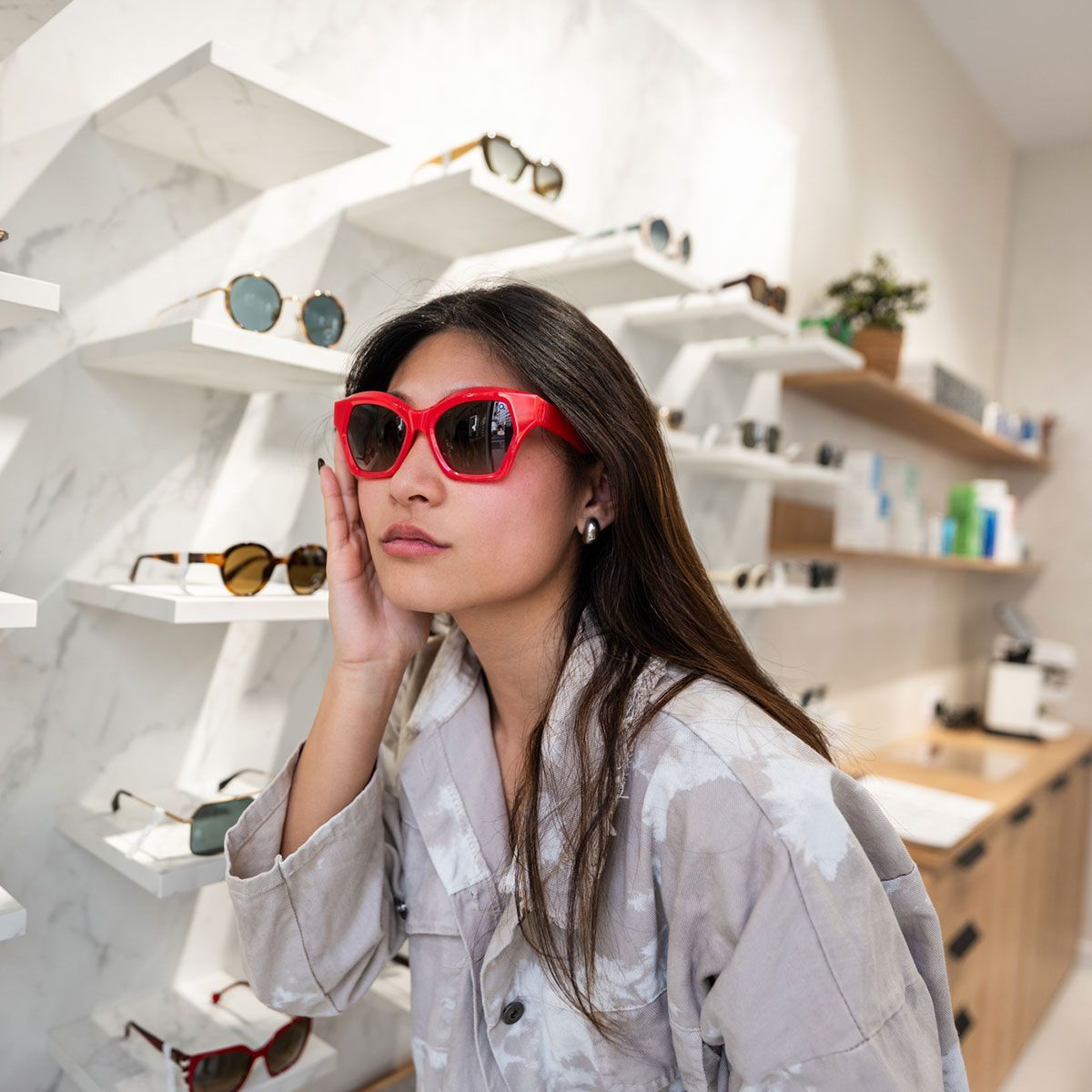 Young woman trying on red sunglasses in optical store Young woman trying on red sunglasses in optical store