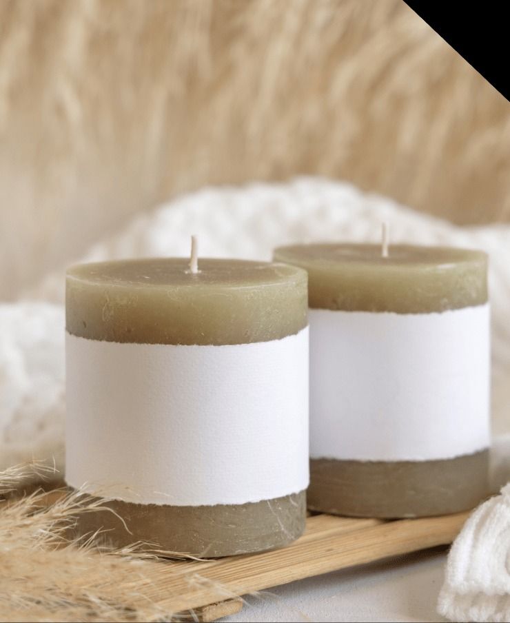 Two cylindrical olive-green candles with white label bands.