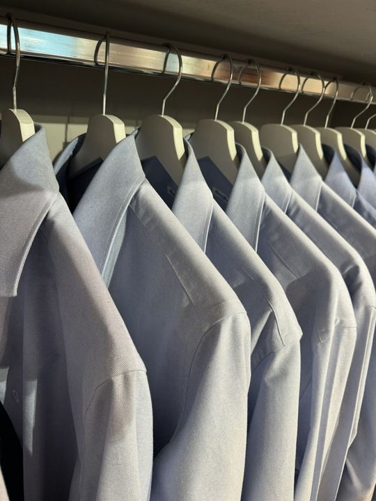 Row of light blue patterned shirts on hangers in a closet or clothing rack