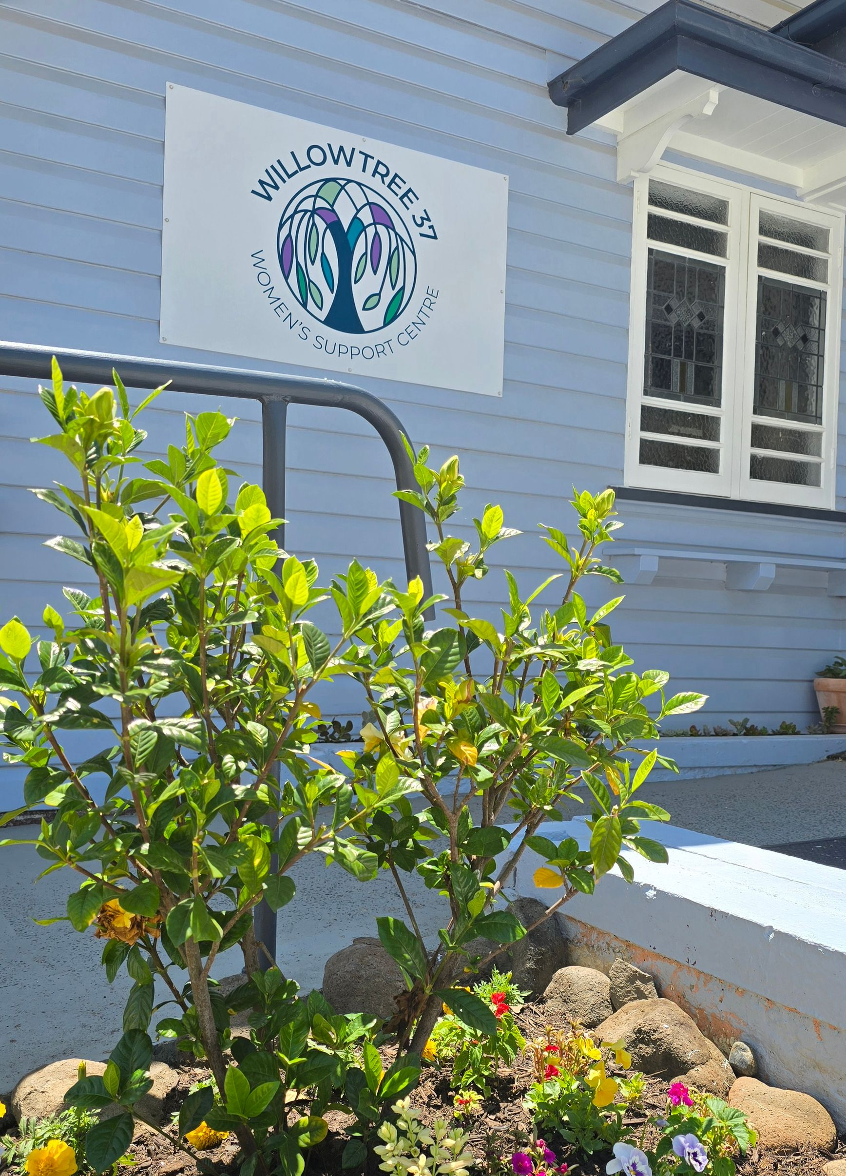 A blue house with a WillowTree 37 Women's Support Centre sign on the front wall. 
