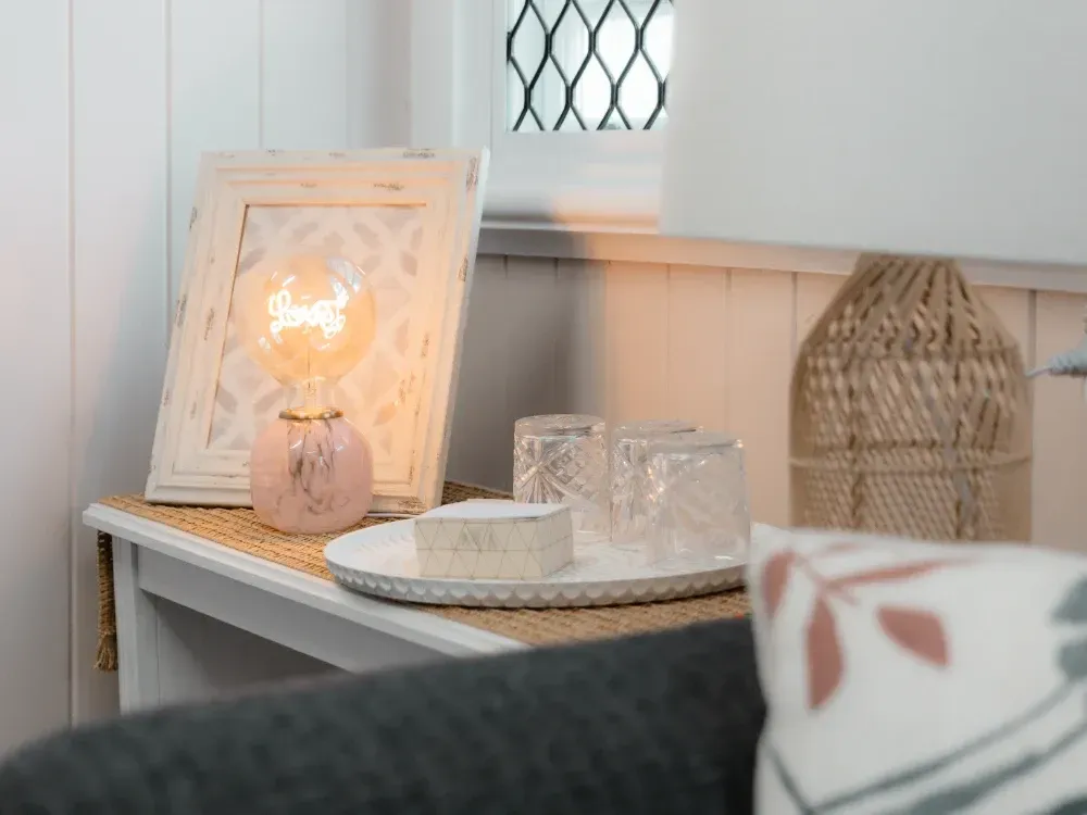 A table with a lamp and a picture on it in a living room.