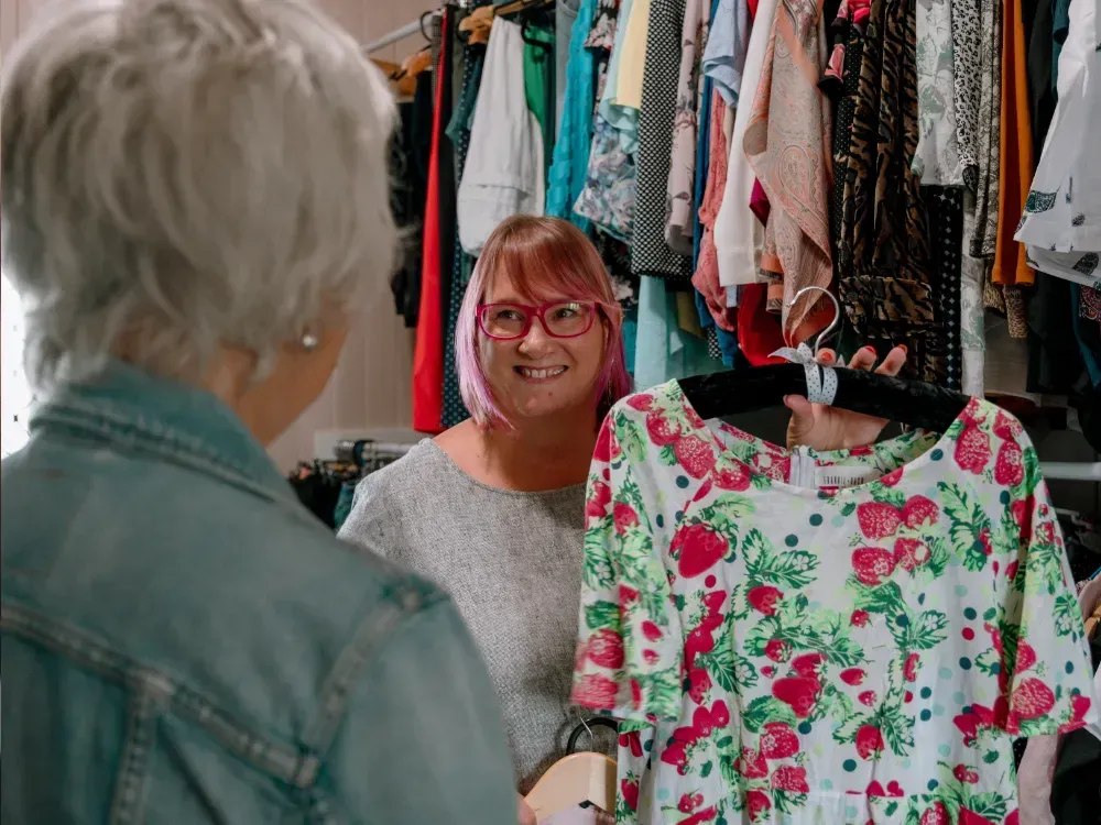 Two women are looking at a floral shirt in a store.