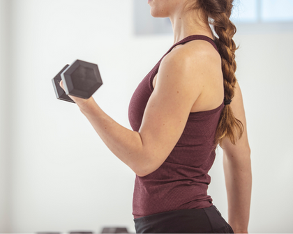 A woman is lifting a dumbbell in a gym