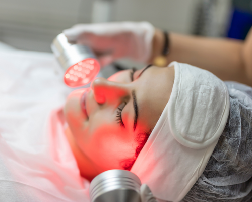 A woman is getting a red light treatment on her face.