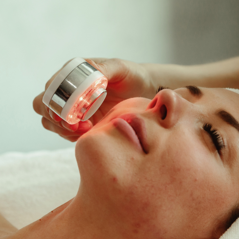 A woman is getting a red light treatment on her face