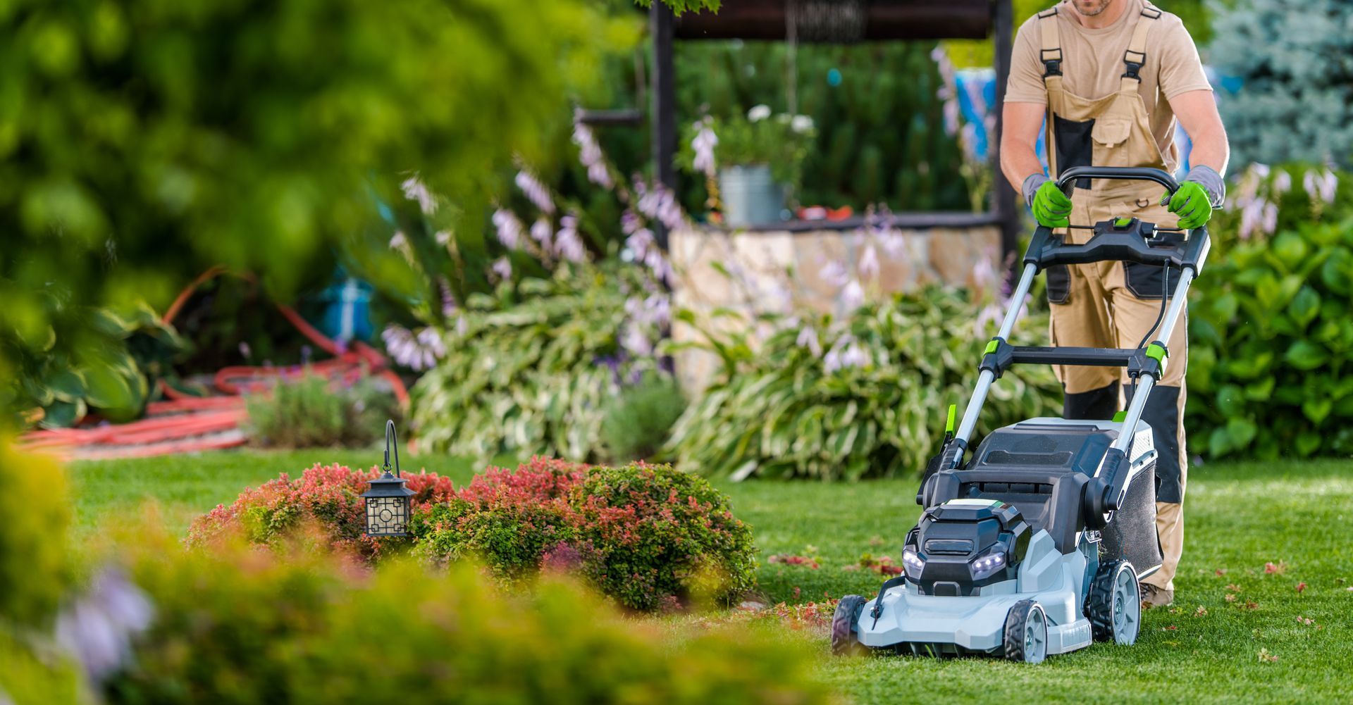 A man is mowing a lush green lawn with a lawn mower.