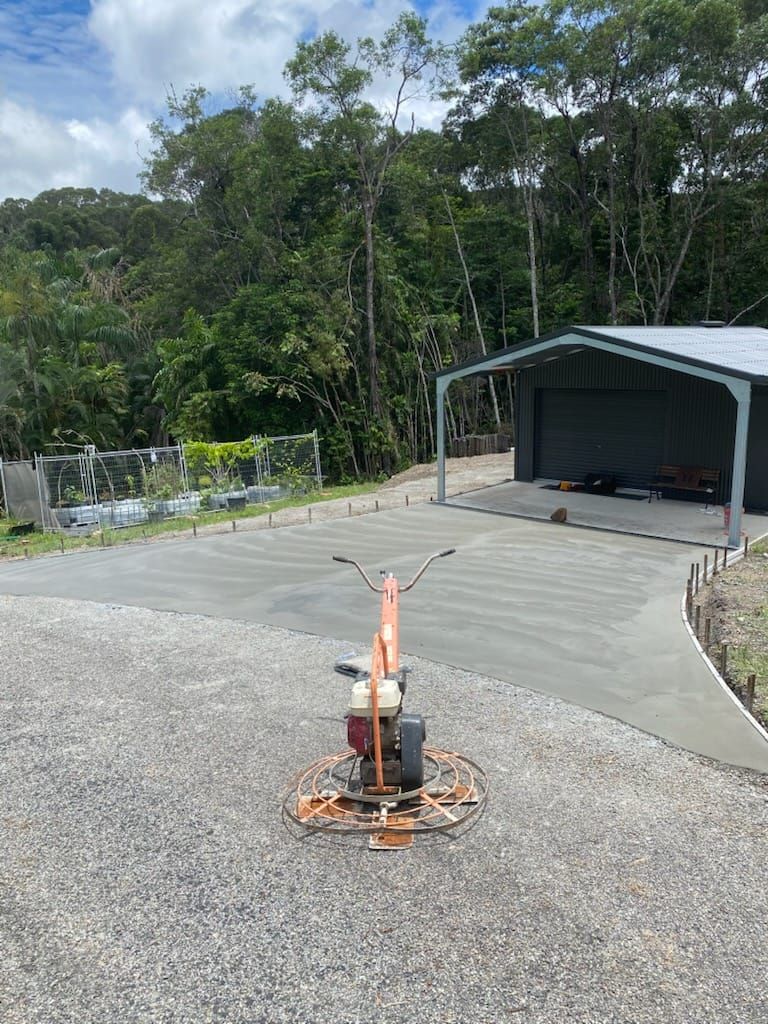 A Machine Is Sitting On Top Of A Gravel Driveway Next To A Building — Core Concrete in Cairns, QLD