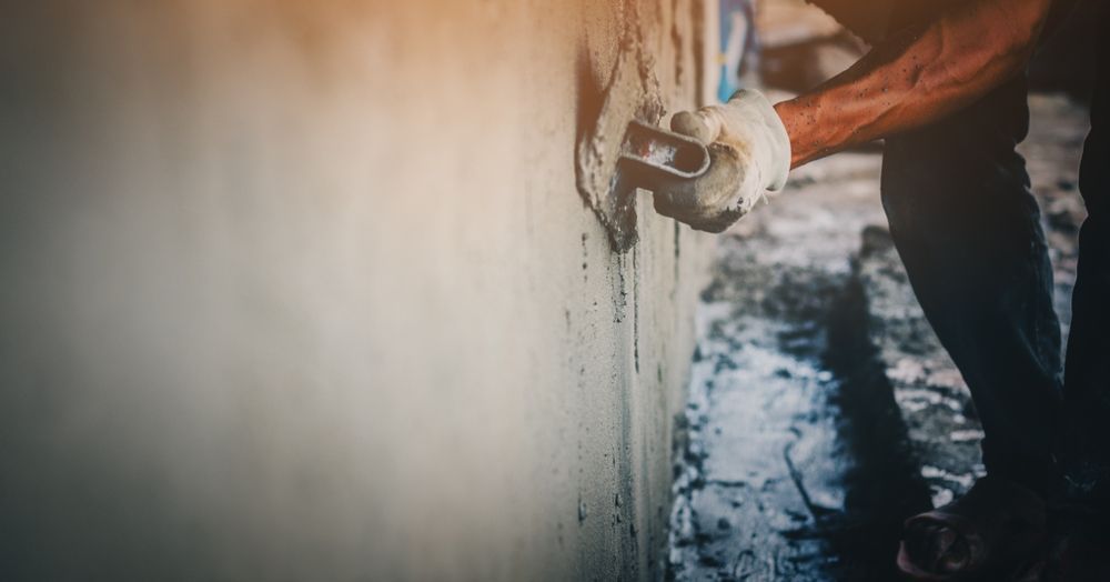 A Man Is Plastering A Wall With A Trowel — Core Concrete in Cairns, QLD