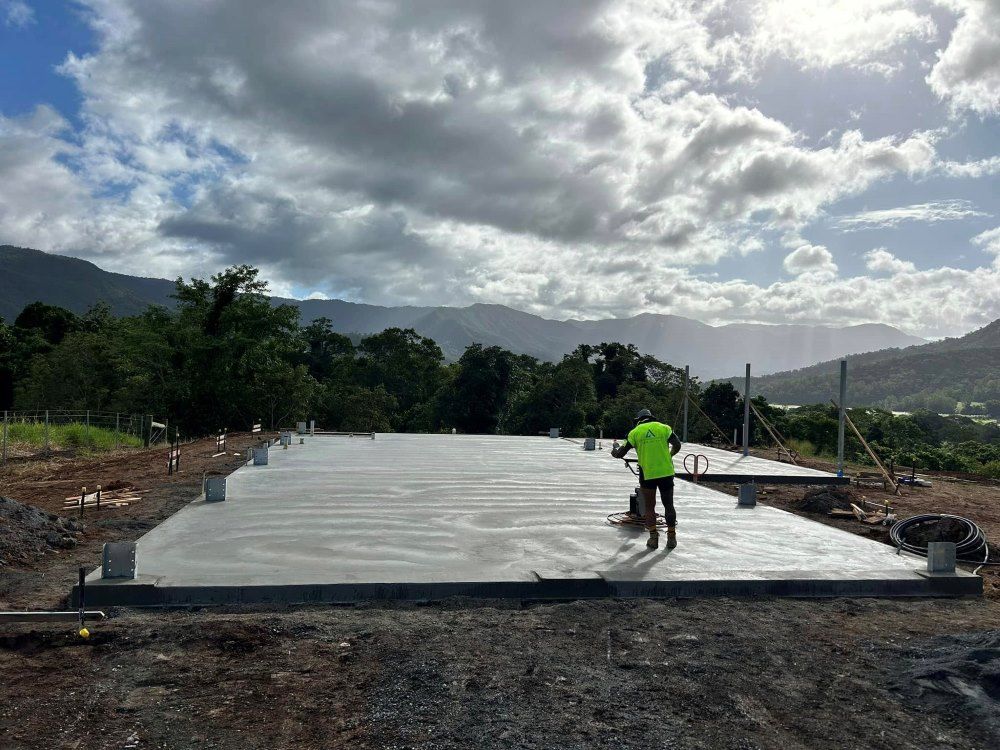 A Man is Standing on a Concrete Floor in a Field With Mountains in the Background — Core Concrete in Port Douglas, QLD