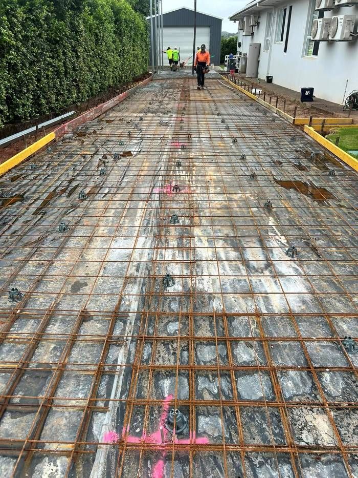 A Man Is Walking Down A Dirt Road With A Grid On The Ground — Core Concrete in Cairns, QLD