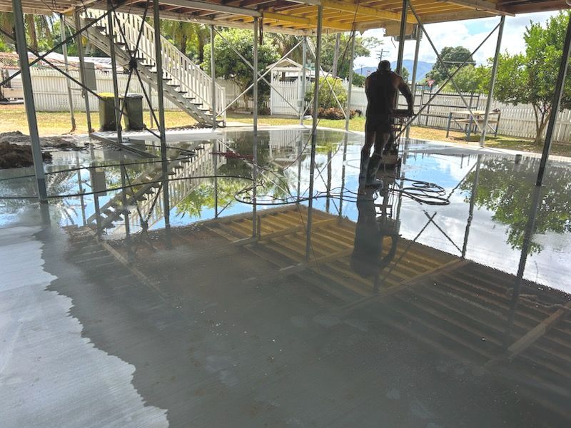 A Man Is Using A Machine To Level A Concrete Floor — Core Concrete in Cairns, QLD