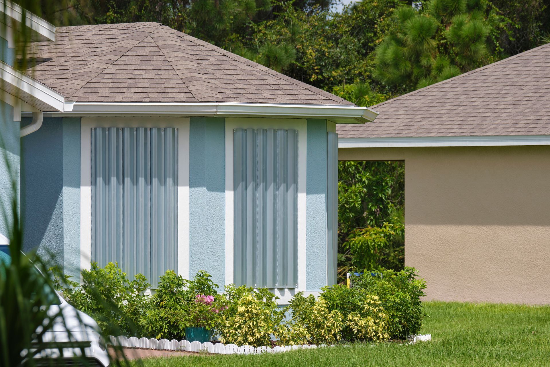 A blue house with white curtains and a brown roof