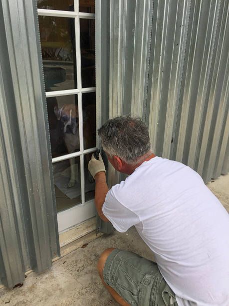 A man is kneeling down in front of a window.