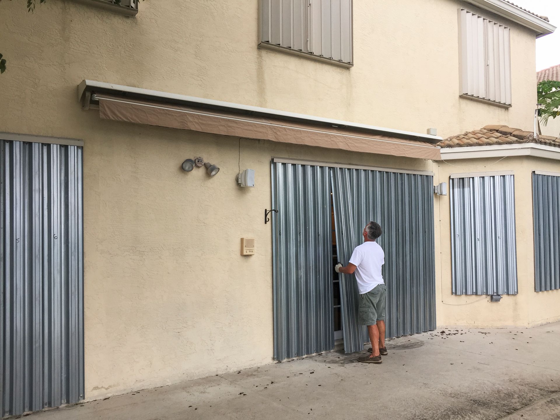 Man completing installation, showcasing professional hurricane shutters for home protection.