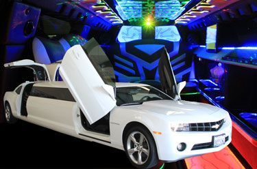 White Camaro limousine with open doors and an interior lit with blue and green lights.