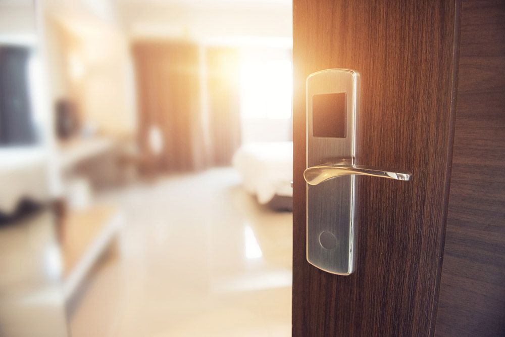 Door with a silver handle open to a sunlit hotel room.
