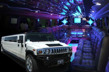 White Hummer limousine with illuminated interior, blue and purple lights.