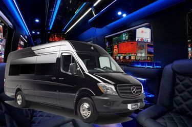 Black Mercedes-Benz passenger van with interior featuring large screens and blue lighting.
