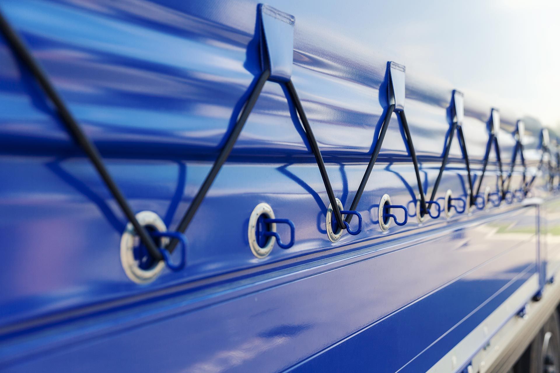 A close-up of a blue truck tarp wrapped around a truck trailer. A close-up of a blue truck tarp wrapped around a truck trailer.