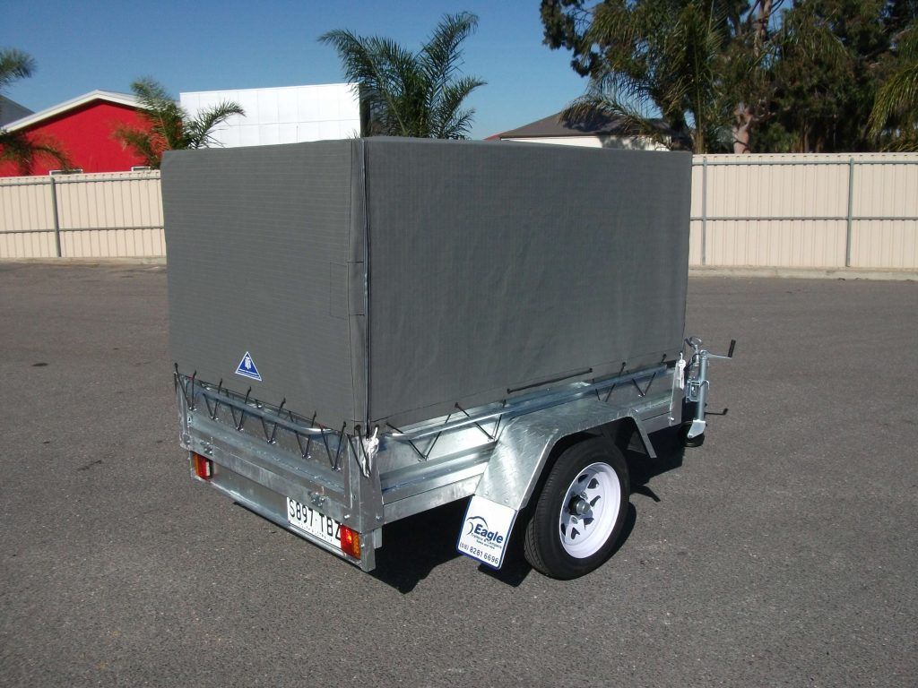 Gray trailer with a canvas cover, parked on asphalt.