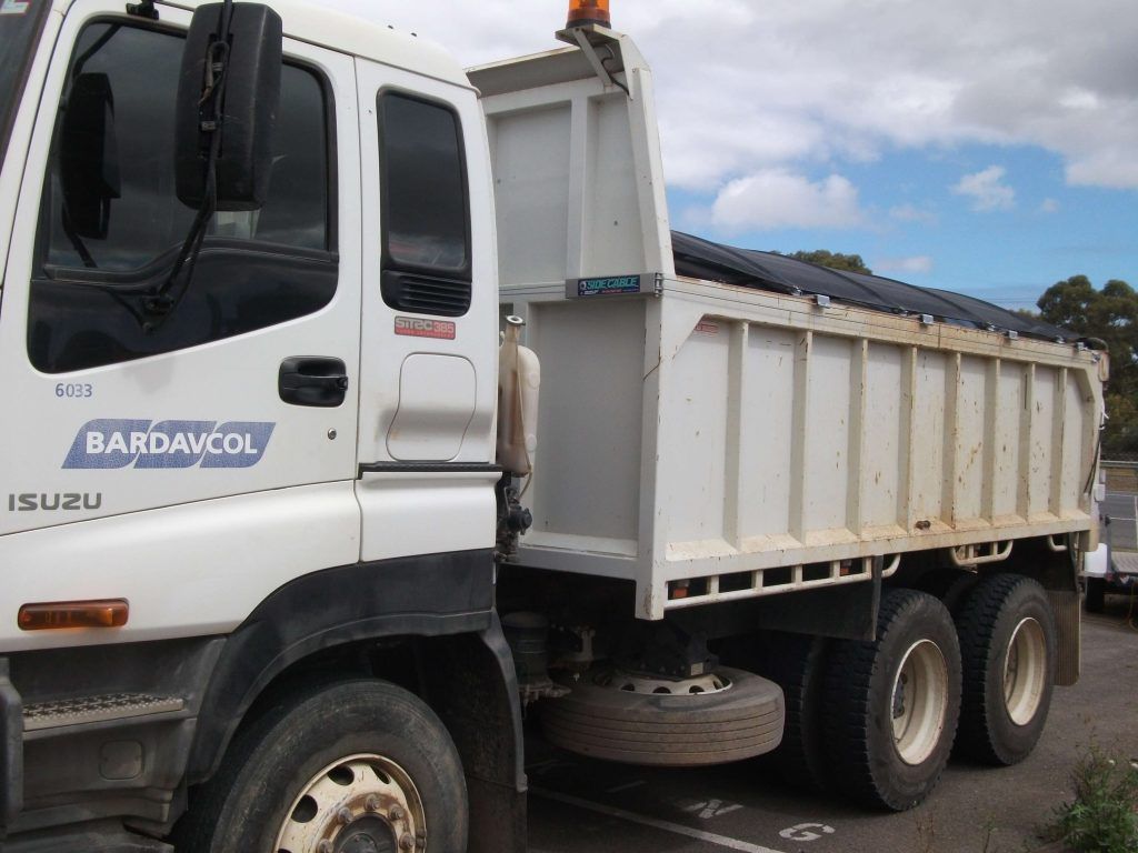 White dump truck with a raised bed, parked outdoors.