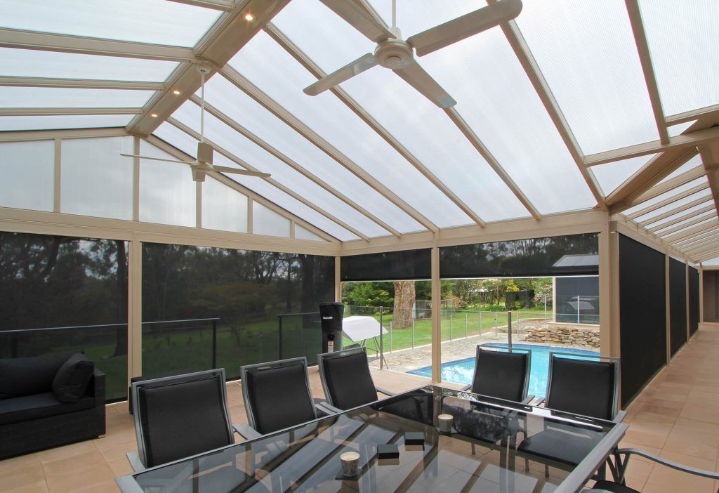 Covered outdoor patio with seating, a pool, and dark shades.