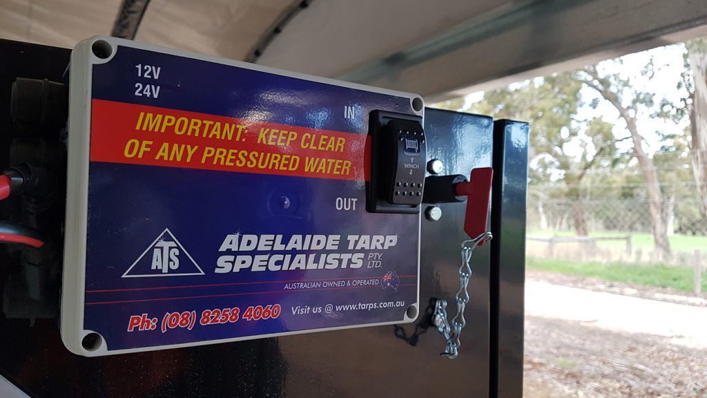 Sign with a switch, cautioning to keep clear of pressurized space. Black box, blue sign with red and white text.