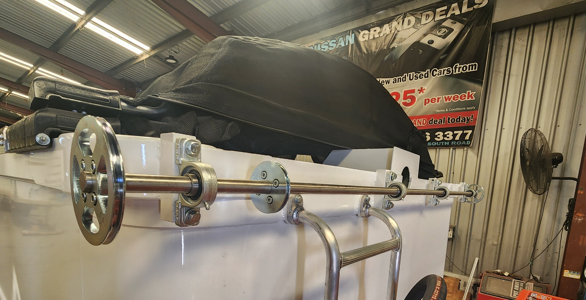 A boat's stern with a stainless steel roller and black cover in a garage setting.