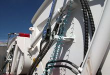 White industrial machinery with black hoses and blue sky.