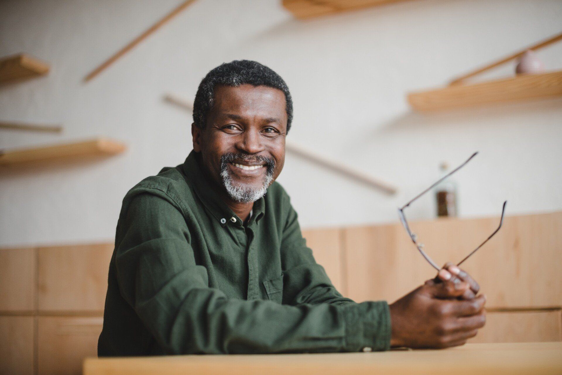 smiling senior black man holding eyeglasses