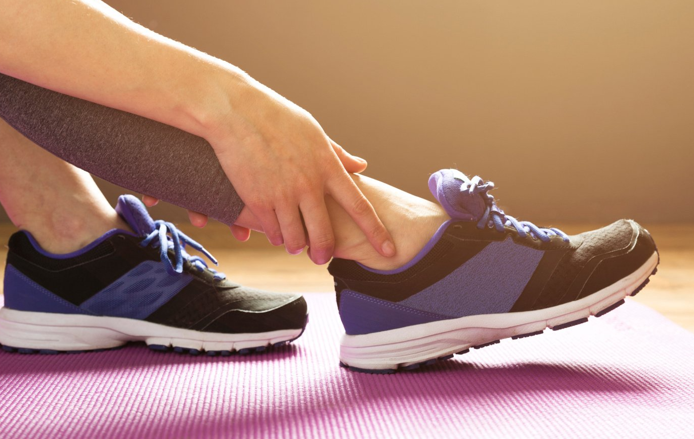 closeup of woman holding injured ankle
