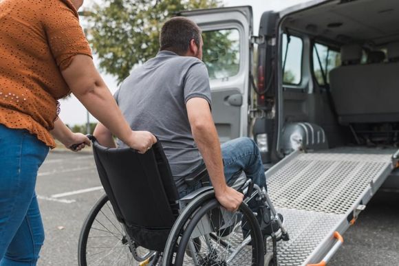 Woman pushing wheelchair up ramp into accessible van.
