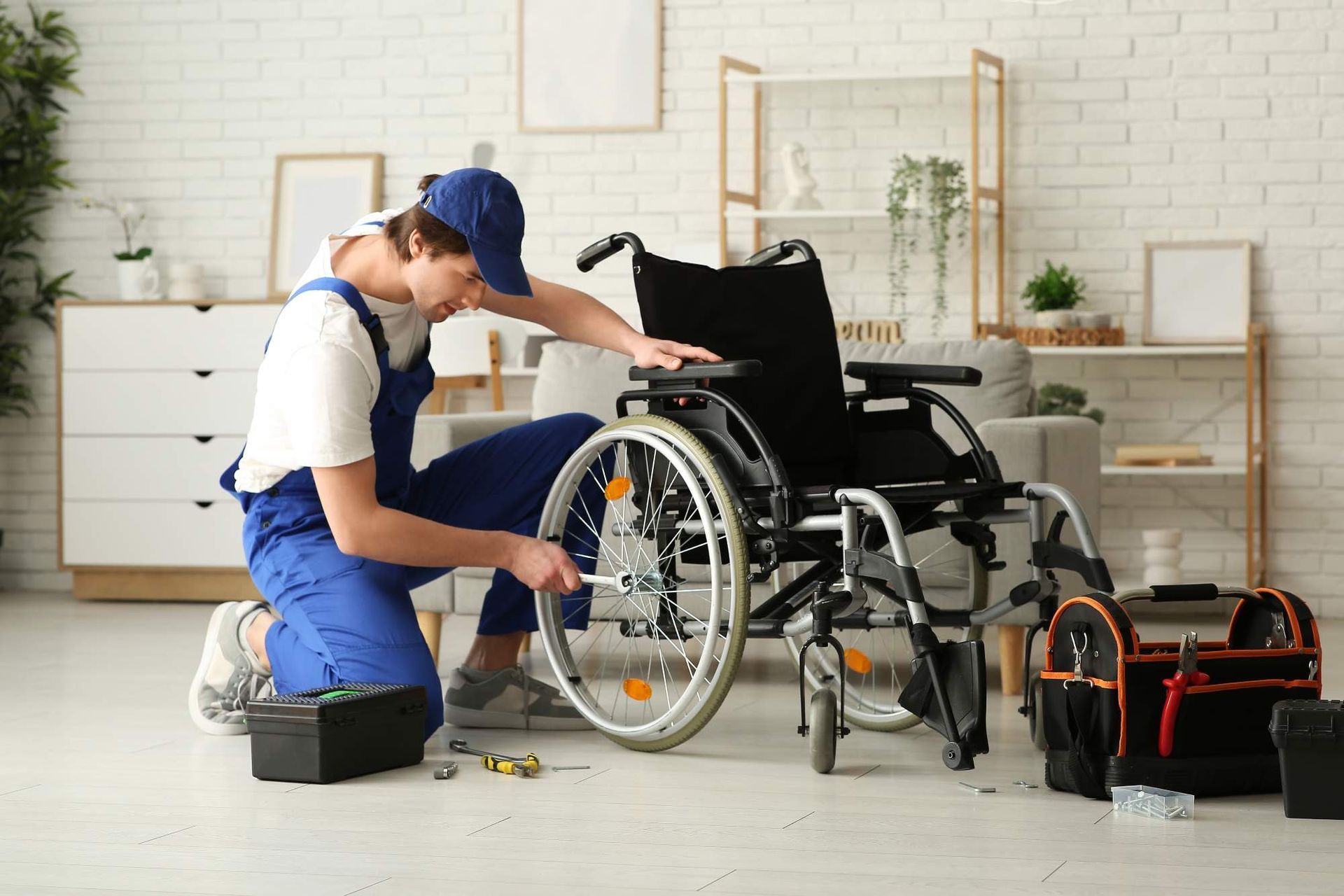 Man in uniform repairs wheelchair in a home. Tools, boxes nearby.