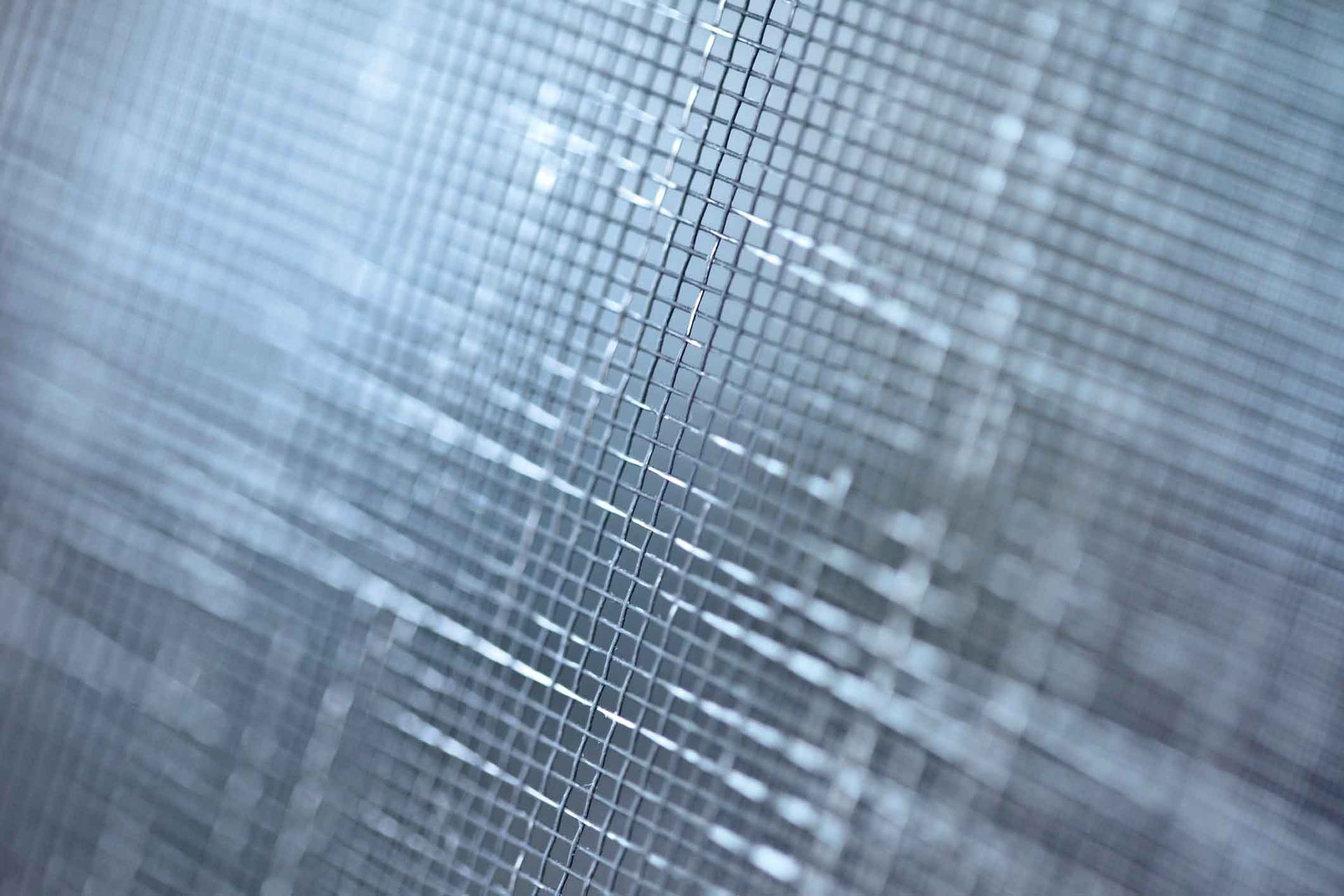 A close up of a mosquito screen on a window.