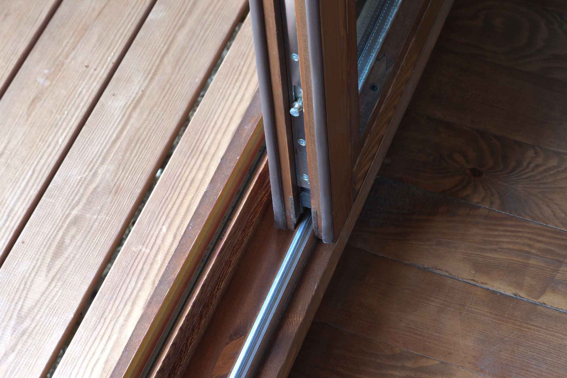 A close up of a wooden sliding glass door on a wooden floor