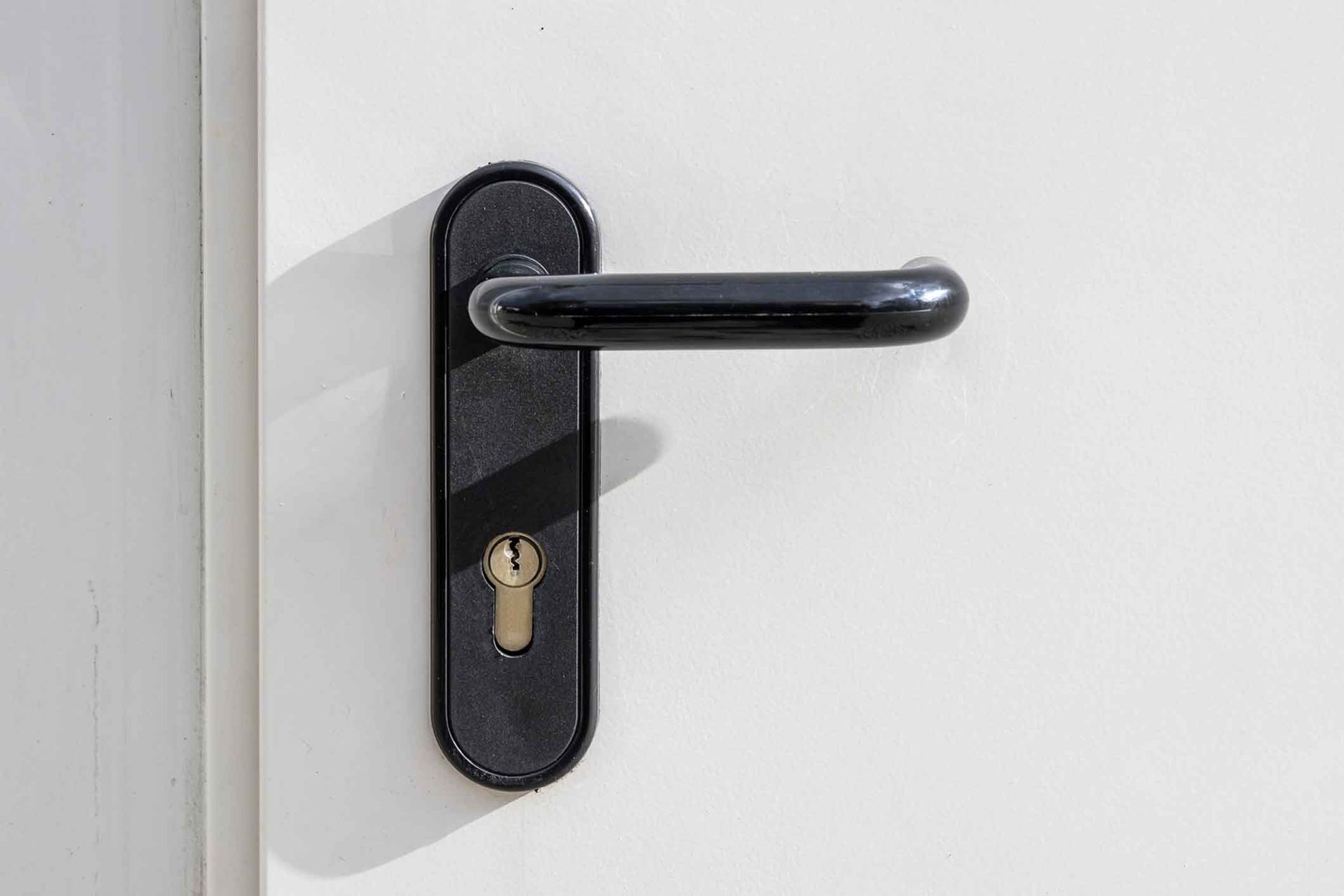 A close up of a door handle on a white door.