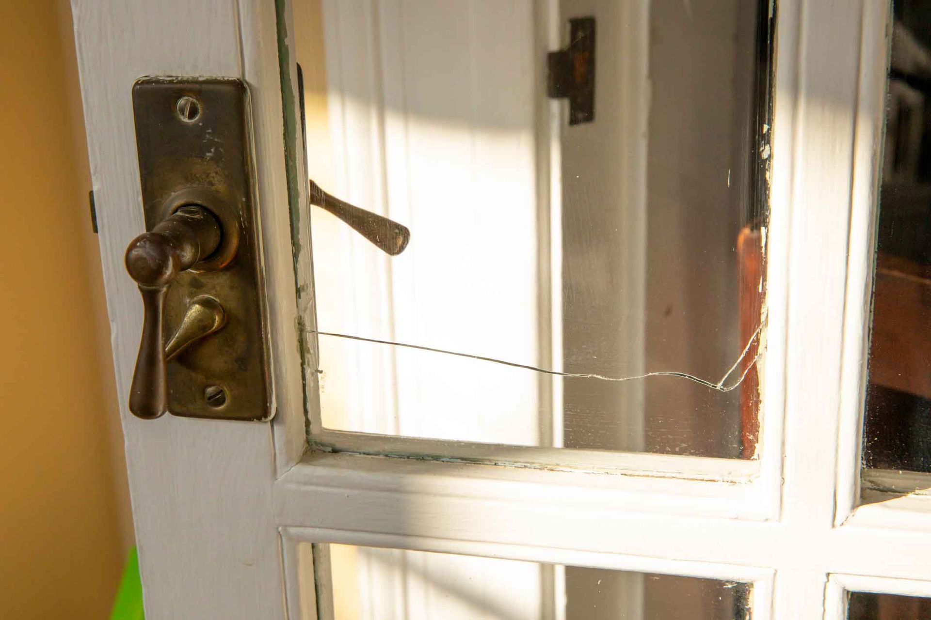A close up of a door with a broken glass window.