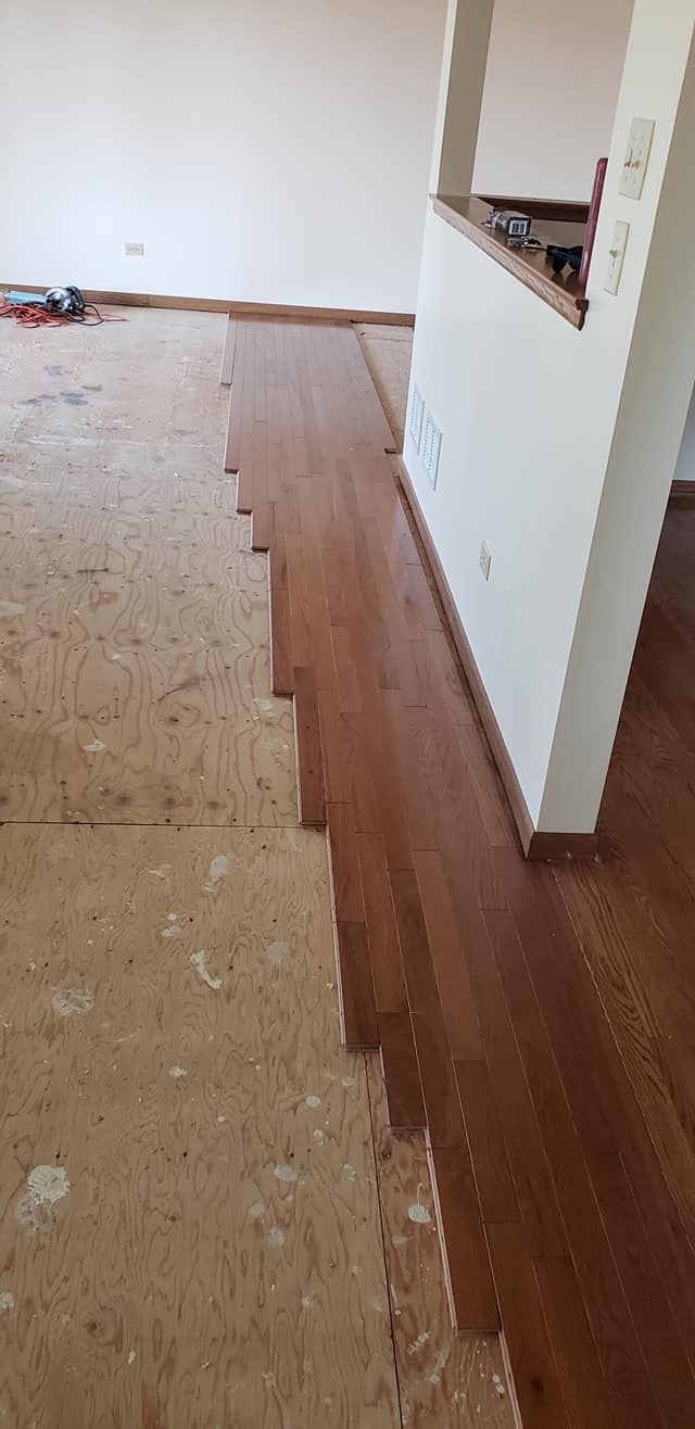 Partially removed carpet reveals wood flooring in a room under renovation.
