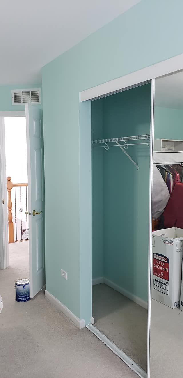 Narrow bedroom hallway with teal walls, white carpet, and a mirrored closet door.
