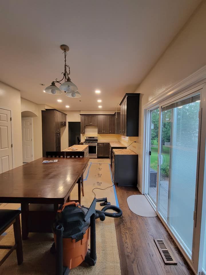 Spacious kitchen with dark island, pendant light, white cabinets, and sliding glass doors to a backyard.
