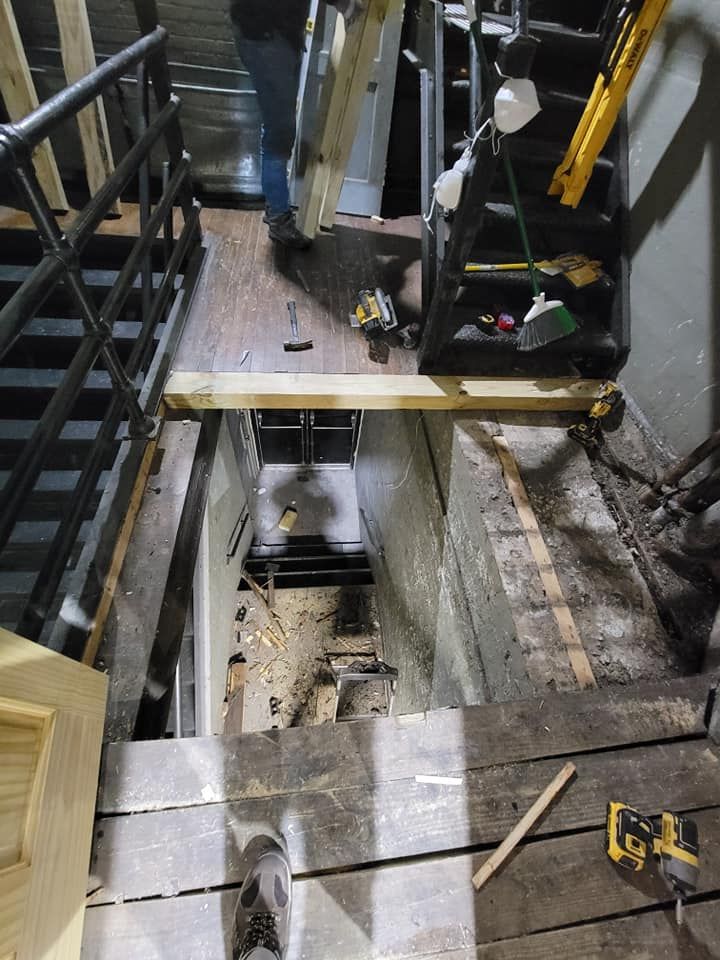 Construction trench with ladders, debris, and wooden planks inside an industrial work area