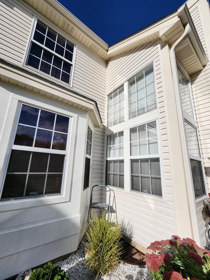 White house exterior with tall windows, corner siding, and small plants by the entryway