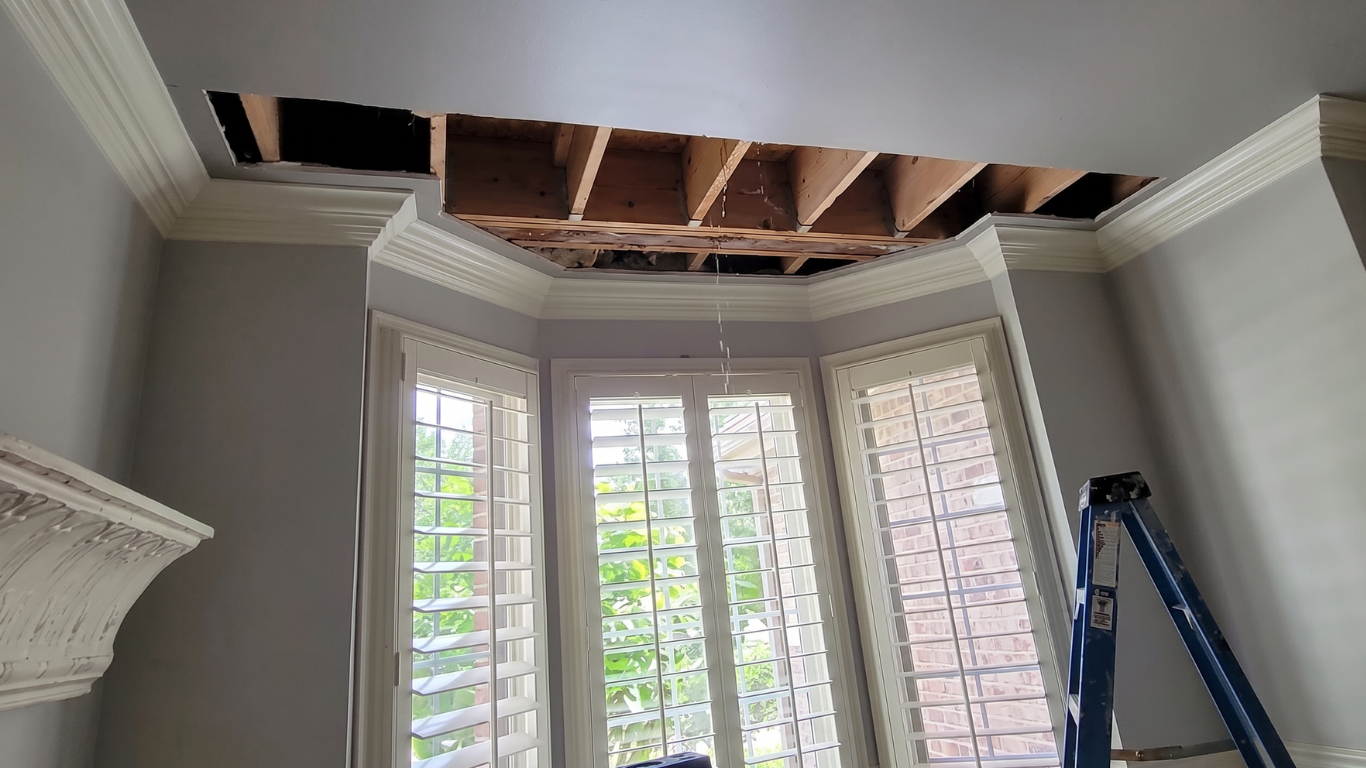 Interior room with bay windows, exposed ceiling beams, and a ladder during renovation.
