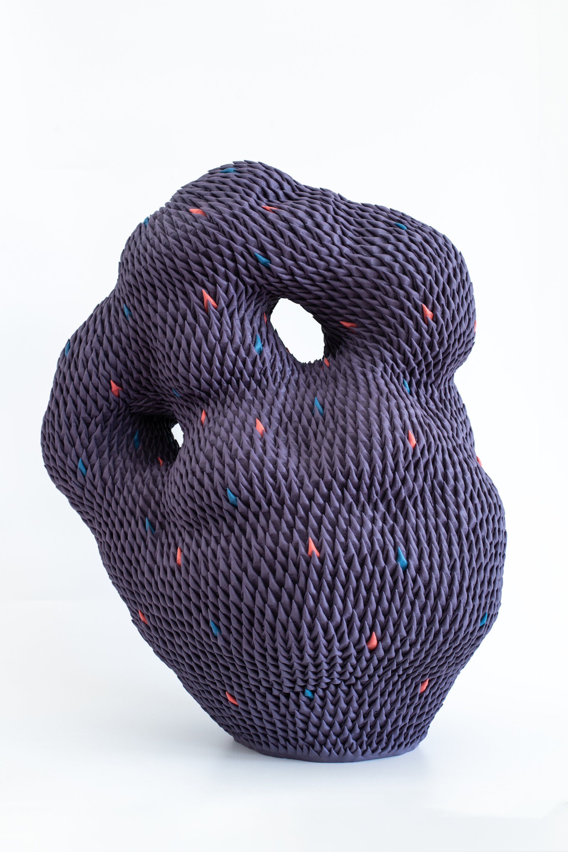 Ceramic sculpture by Japanese artist Sayuri Ikake. This purple work is made up of small spikes applied one by one. With a complex and rounded shape, it features openwork parts.